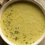 Eine große Schüssel mit Brokkoli Käse Suppe steht auf dem Tisch.