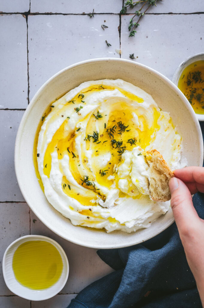 Eine Person dippt ein Stück Brot in den Feta Dip.