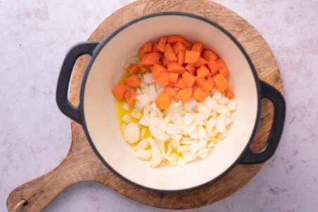 Karotten, Zwiebeln und Knoblauch werden in einem Topf angeschwitzt.