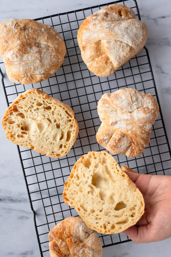 Eine Person nimmt sich ein Brötchen von dem Rost.