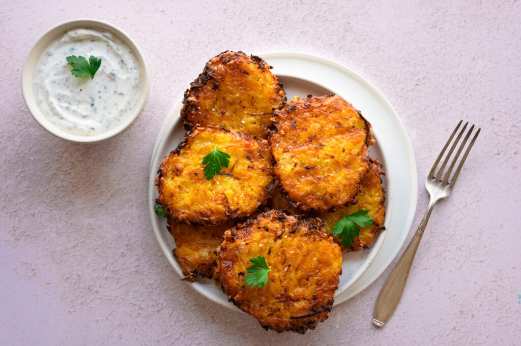 Ein Teller mit Kartoffelpuffern mit Käse und Kräuterquark.