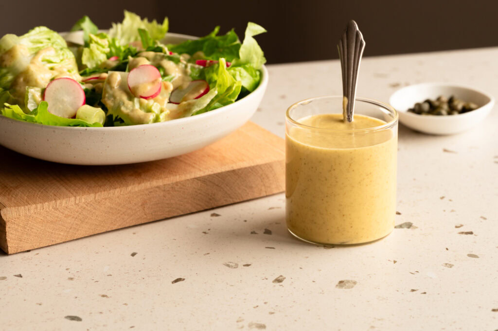 Ein Salat wird mit Kaperndressing garniert.