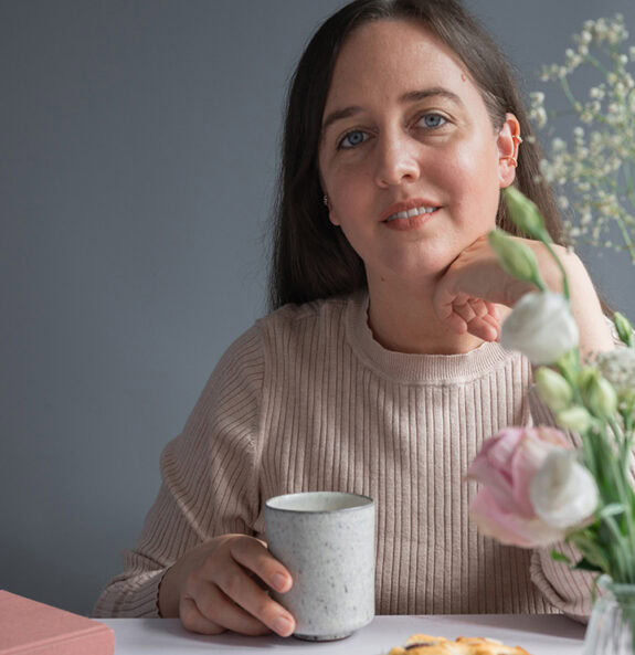 Eine Frau sitzt an einem Tisch und trinkt Kaffee.