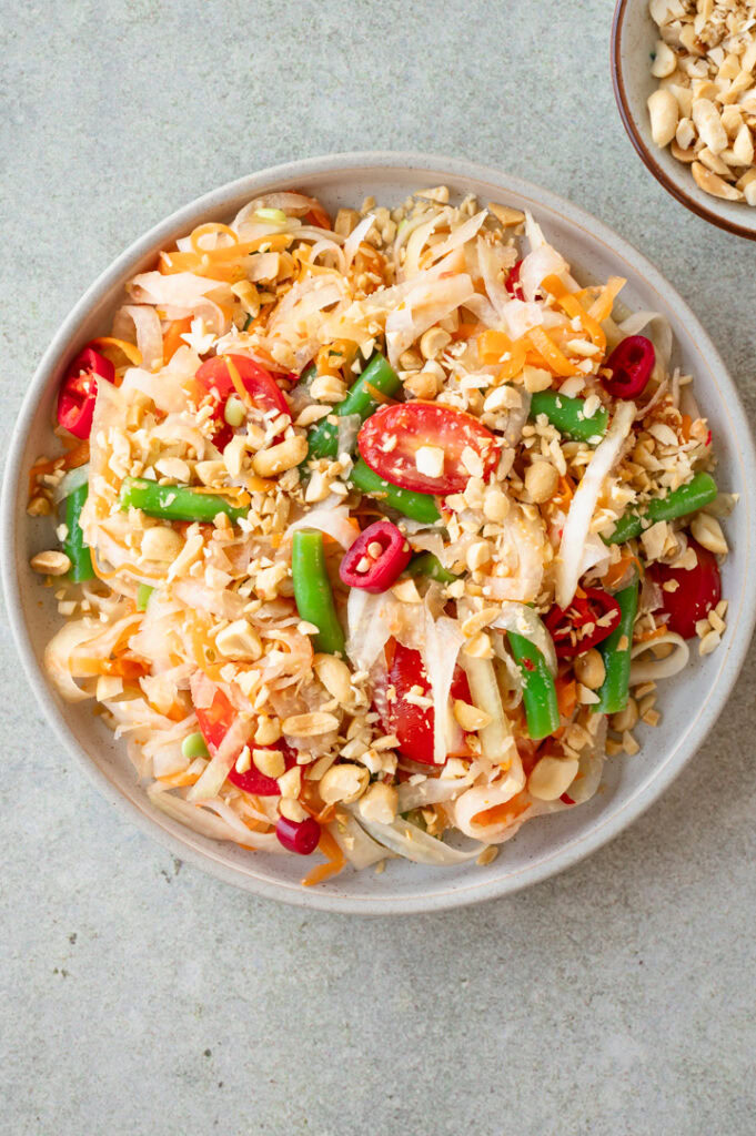 Eine Schüssel mit thailändischem Kohlrabi-Salat mit Erdnüssen stehen auf dem Tisch.
