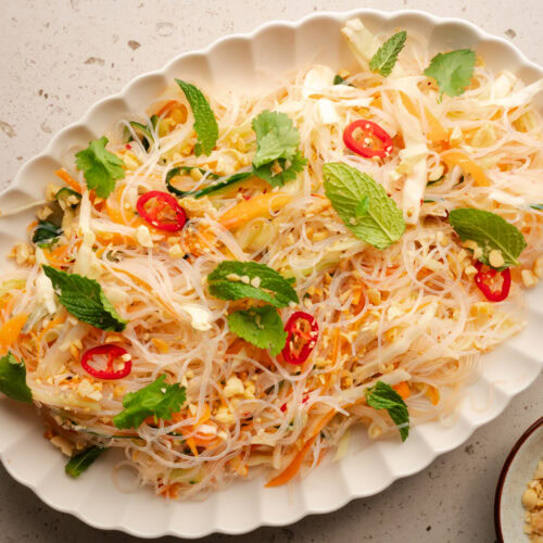 Eine Servierplatte mit asiatischem Glasnudelsalat steht auf einem Tisch.