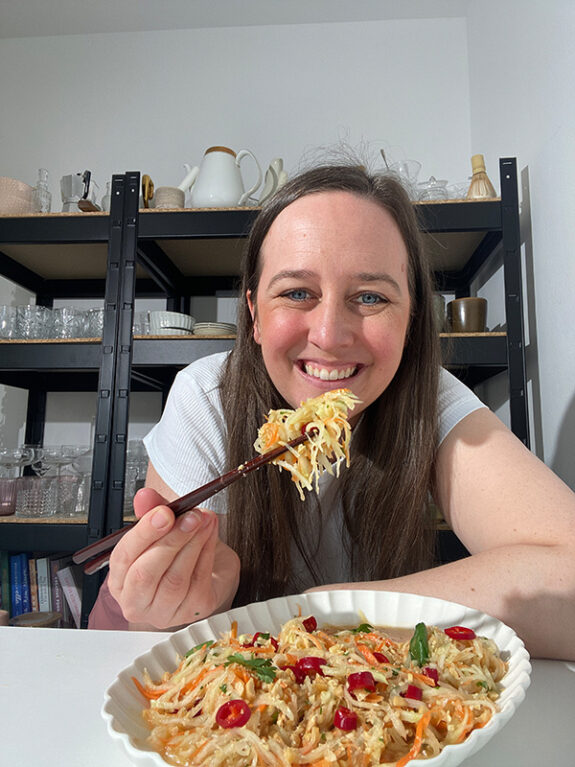 Eine Frau isst den Kohlrabisalat mit Stäbchen.