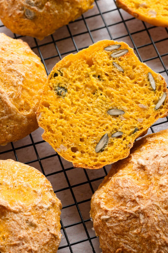 Ein angeschnittenes Kürbisbrötchen liegt auf einem Gitter zum Abkühlen.