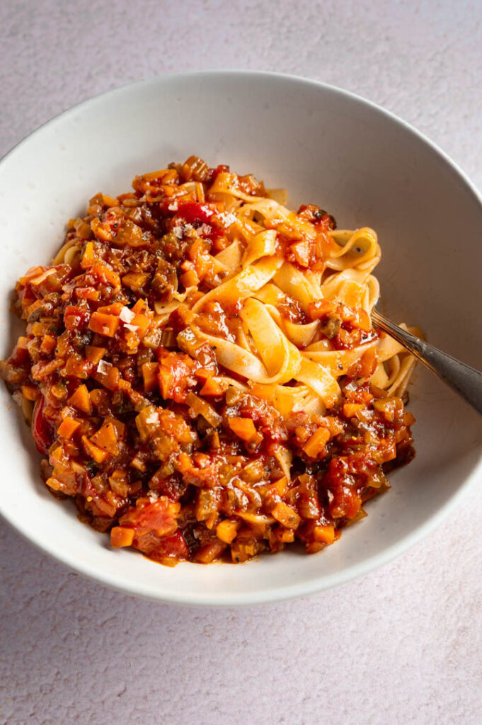 Ein Teller mit Bandnudeln und vegetarischer Bolognese steht auf dem Tisch.