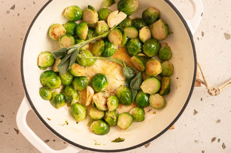 Butter, Salbei und Knoblauch werden zu dem Rosenkohl gegeben.