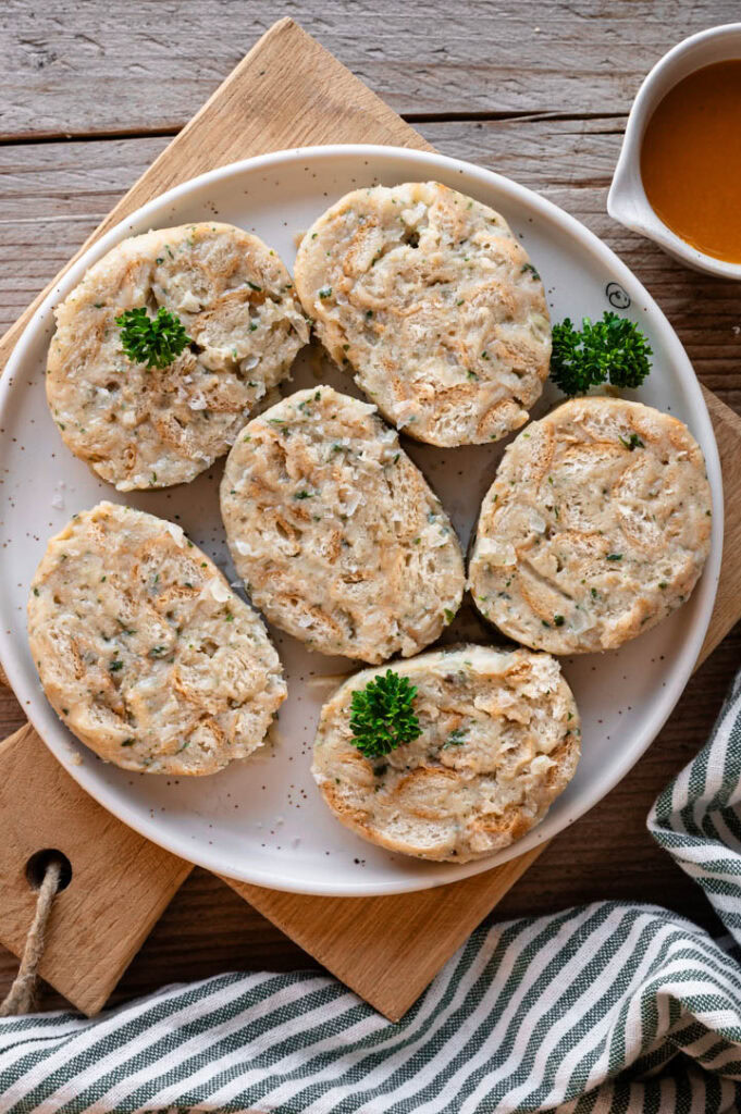 Eine große Portion Serviettenknödel und eine Sauciere mit Bratensauce stehen auf dem Tisch.