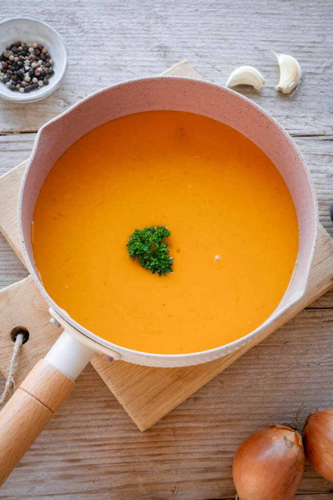 Ein Topf mit vegetarischer Bratensauce steht auf einem rustikalem Tisch.