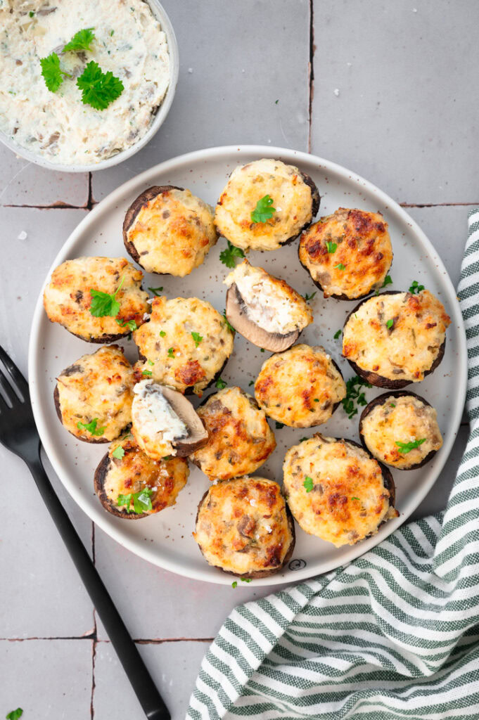 Ein Teller mit vegetarisch gefüllten Champignons steht auf einem Tisch.