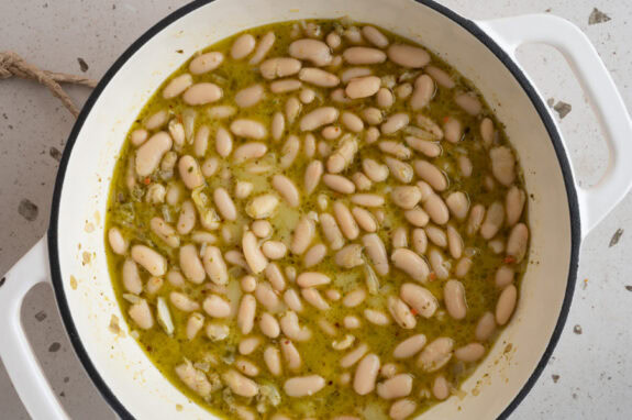 Die Cannellini Bohnen und die Gemüsebrühe werden in die Pfanne gegeben.