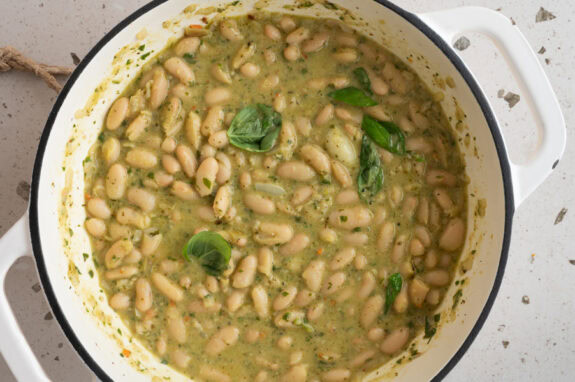 Kräuter und Parmesan werden zu den Cannellini Bohnen in Pesto gegeben.