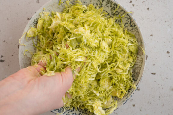 Das Dressing wird mit den Händen in den Rosenkohl einmassiert.