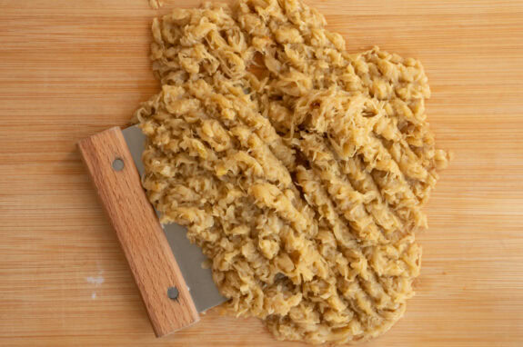 Die karamellisierten Zwiebeln werden auf einem Brettchen klein geschnitten.