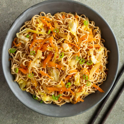 Ein Teller mit gebratenen Mie Nudeln mit Gemüse ohne Ei steht auf dem Tisch.