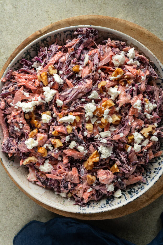 Ein gedeckter Tisch mit cremigem Rotkohlsalat mit Feta und Walnüssen steht auf einem Tisch.