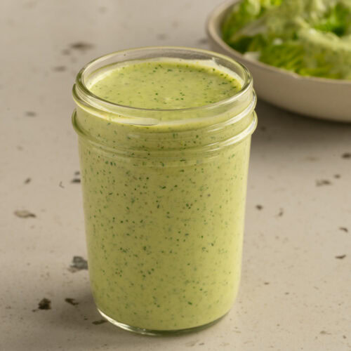 Ein Glas mit Joghurt Dill Dressing steht auf einem Tisch.