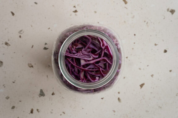 Der fein gehobelte Rotkohl wird in ein Weckglas gegeben.