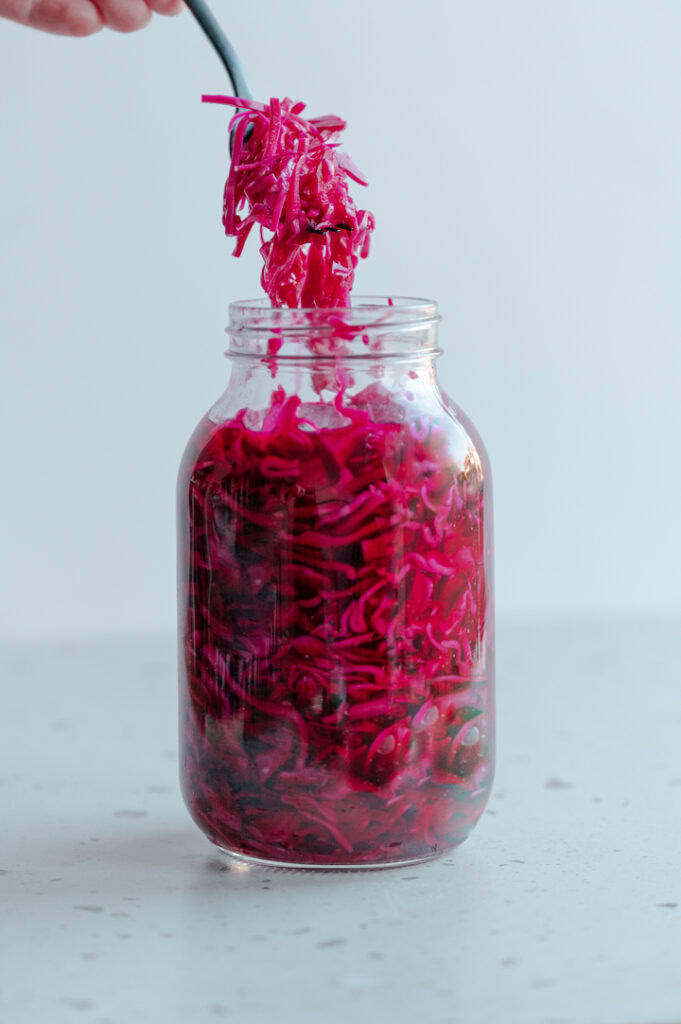 Eine Person nimmt etwas eingelegten Rotkohl aus einem Glas.