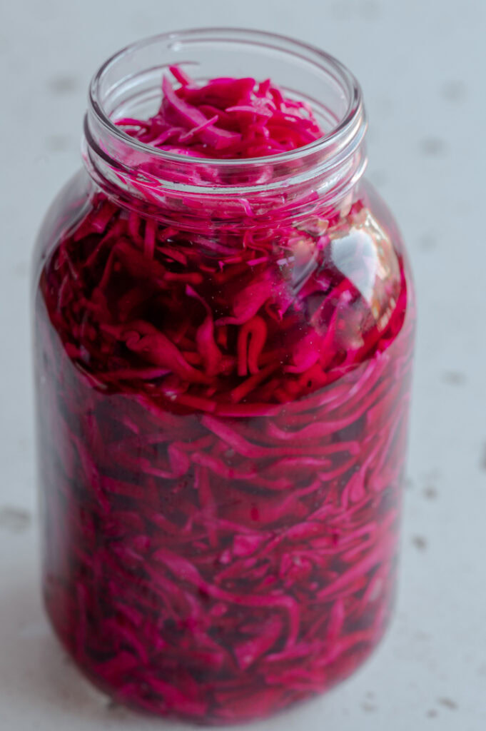 Ein offenes Einmachglas mit eingelegtem Rotkohl steht auf dem Tisch.