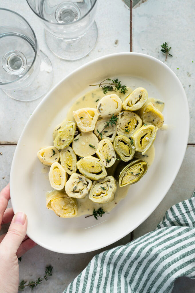 Eine Person stellt den Lauch aus dem Ofen auf den Tisch.