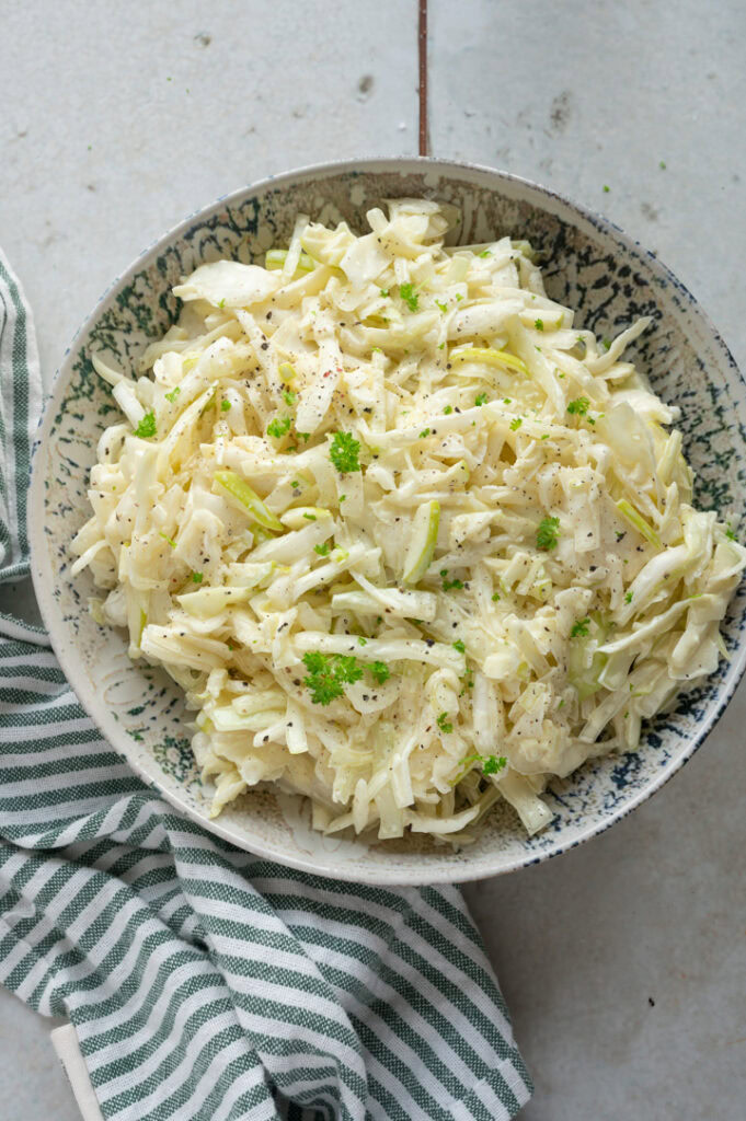 Der Krautsalat mit Mayo und Apfel ist in einer Schüssel.