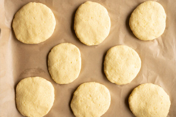 Die geformten Kartoffeltaler liegen auf einem Backblech mit Backpapier.