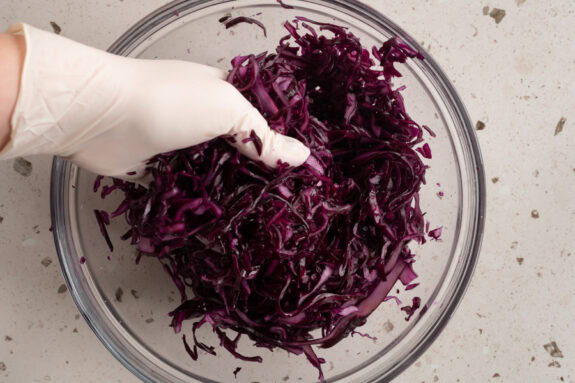 Eine Person vermengt den Salat mit den anderen Zutaten.