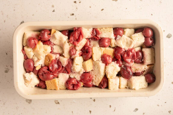 Brotwürfel und Kirschen sind in einer Auflaufform.