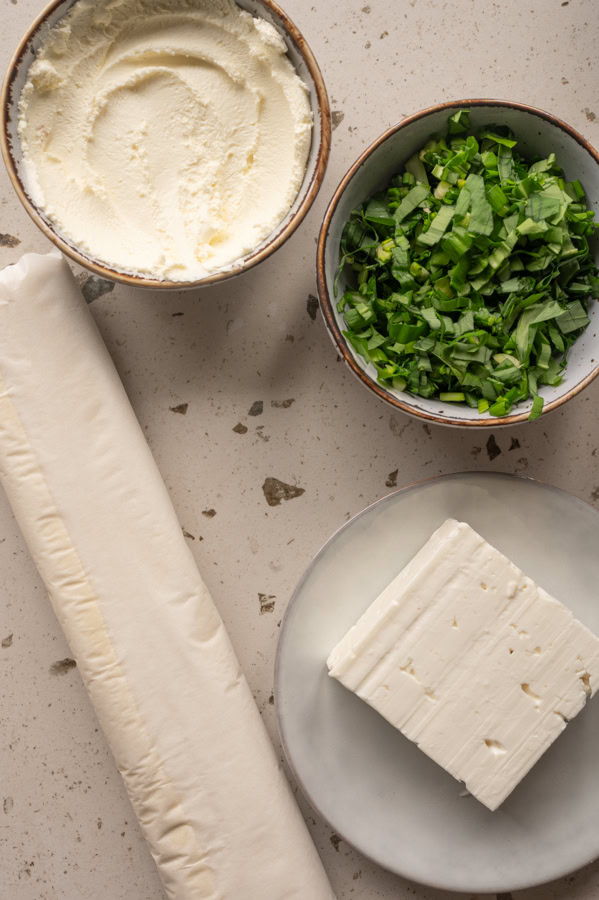 Die Zutaten für die Bärlauchschnecken mit Feta stehen auf einem Tisch.