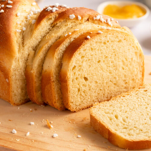 Eine angeschnitte Brioche liegt auf einem Brett.