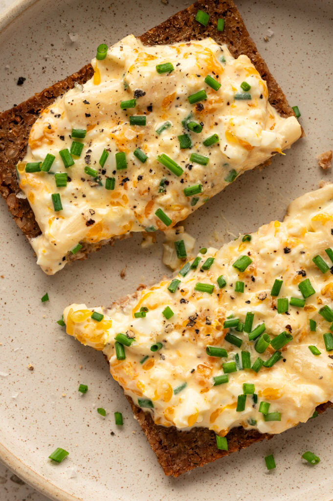 Ein angeschnittenes Brot ist mit dem Eiersalat mit Mandarinen belegt.