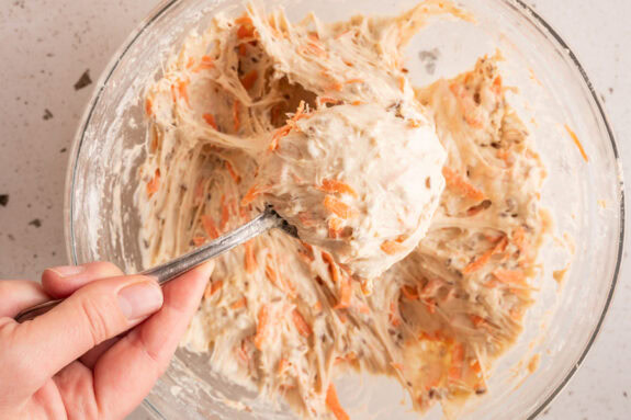 Eine Person nimmt mit einem Löffel den Teig aus der Schüssel.