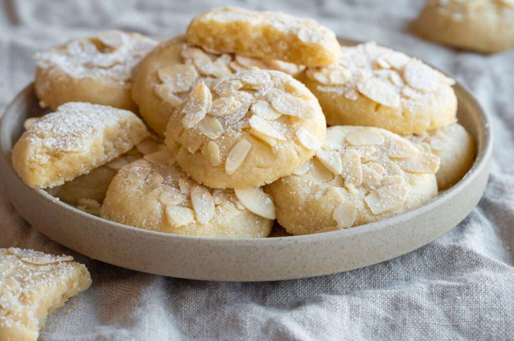 Die Marzipankekse mit Zitrone liegen auf einem Teller.
