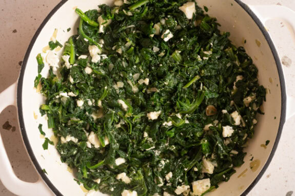 Der Feta wird zu dem Spinat gegeben.