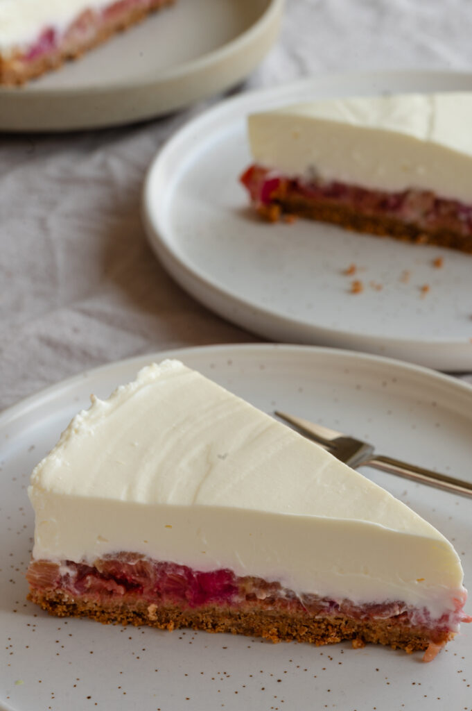 Drei Teller mit je einem Stück Rhabarber Cheesecake.