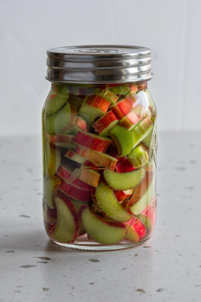 Ein Glas mit konserviertem Rhabarber steht auf einer Arbeitsplatte.