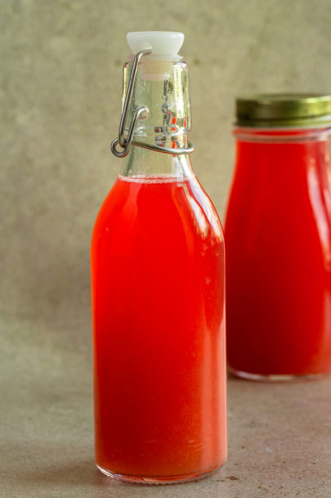 Zwei Flaschen mit selbst gemachtem Rhabarber Sirup stehen auf dem Tisch.