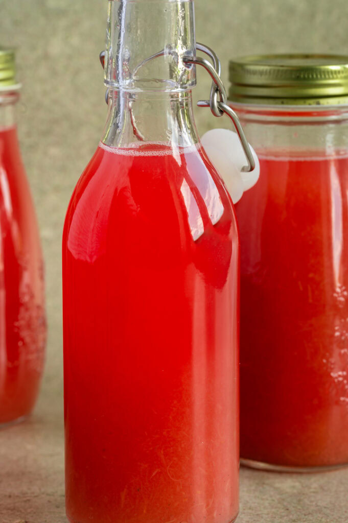 Drei Flaschen mit Rhabarbersirup stehen auf dem Tisch.