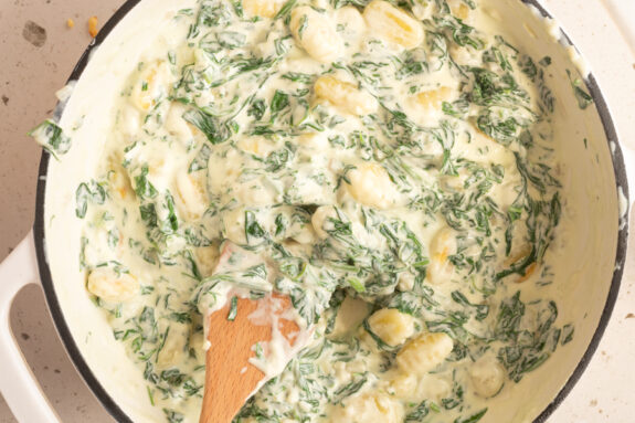 Die Pfanne mit Gnocchi in Spinat Sahnesauce steht auf dem Tisch.