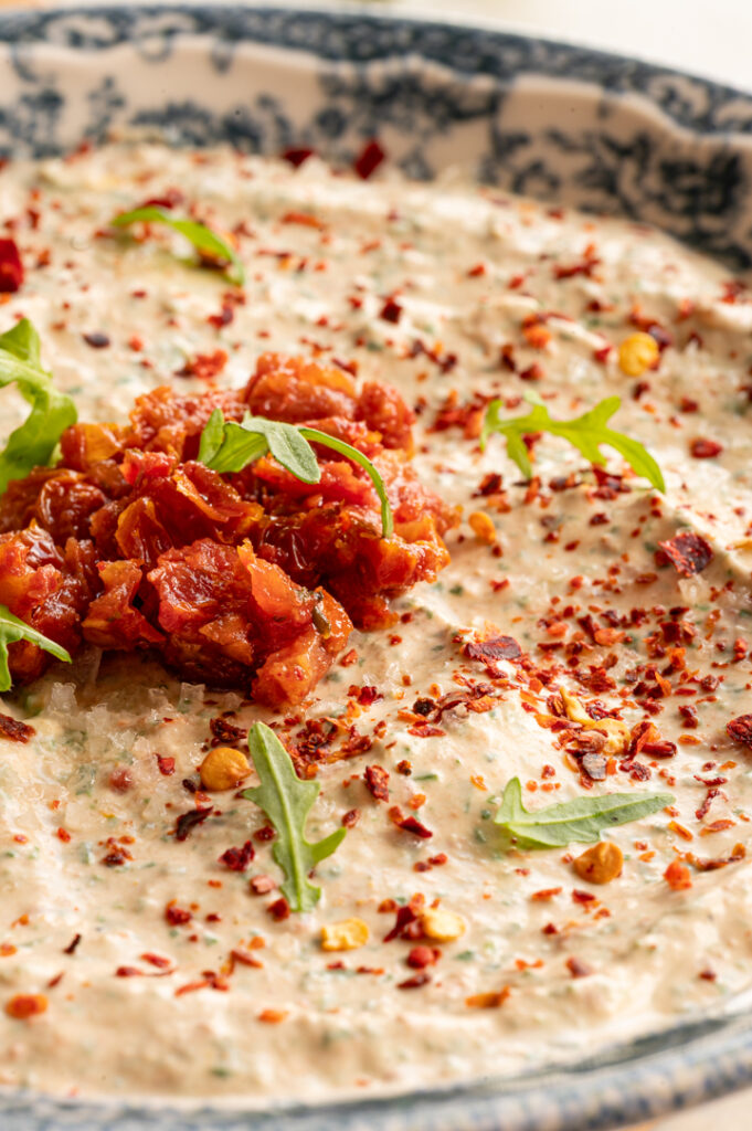 Eine Nahaufnahme des Rucola Dips mit getrockneten Tomaten.