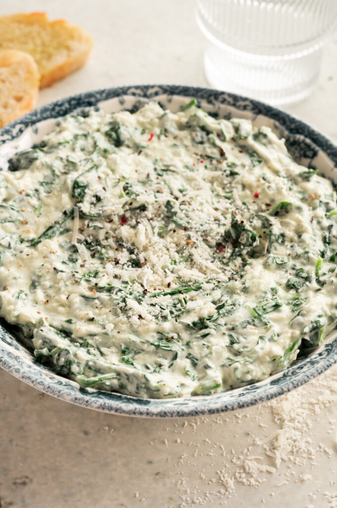 Die Schüssel mit dem cremigen Spinat Dip mit Parmesan steht auf dem Tisch.
