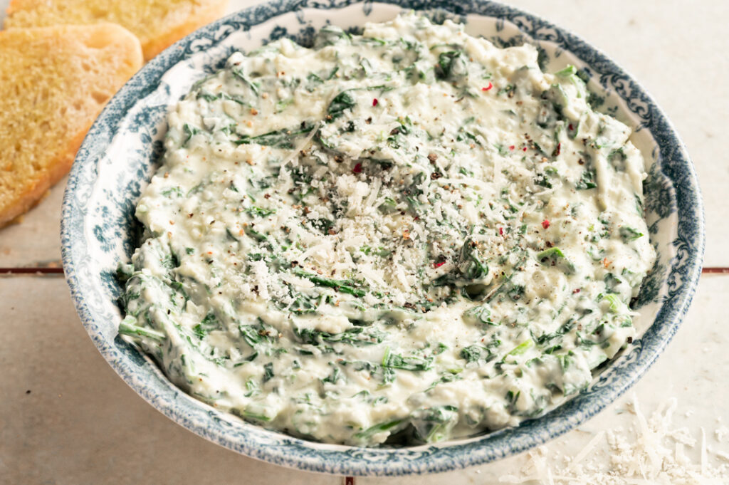 Eine Schüssel mit dem cremigen Spinat Dip steht auf den Tisch.