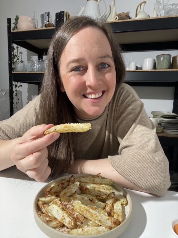 Eine Frau isst ein Stück Kohlrabi aus dem Airfryer.