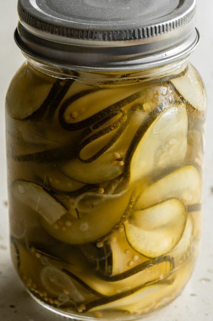 Ein Weckglas mit der eingelegten Zucchini steht auf dem Tisch.
