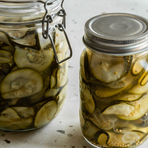 Zwei Gläser mit eingelegter Zucchini stehen auf dem Tisch.