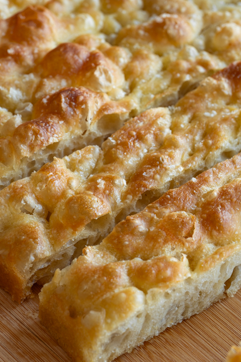 Eine angeschnittene Focaccia liegt auf einem Brett.