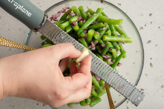 Eine Person reibt den Knoblauch fein.